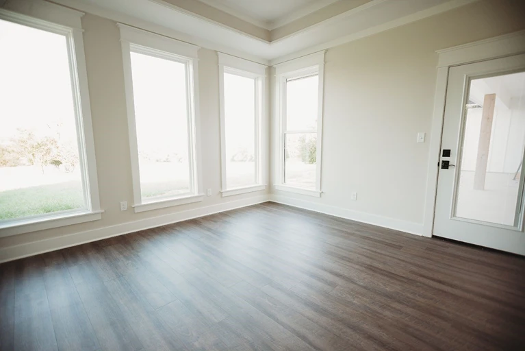 Hardwood flooring in a white living room with windows 